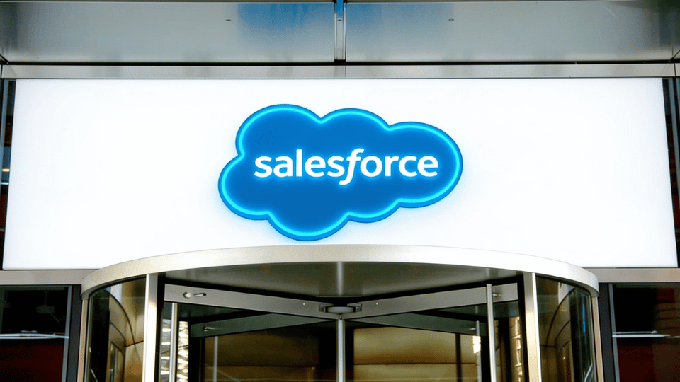 The glowing blue cloud logo of Salesforce mounted above a glass revolving door entrance, perfectly matching the corporate exterior