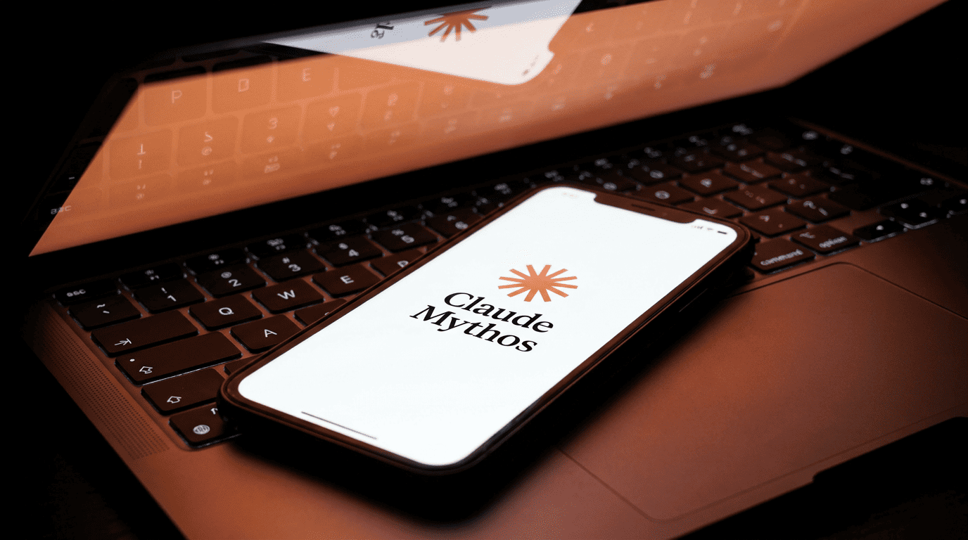 A glowing smartphone displaying the Claude Mythos app logo on top of a dark laptop keyboard.