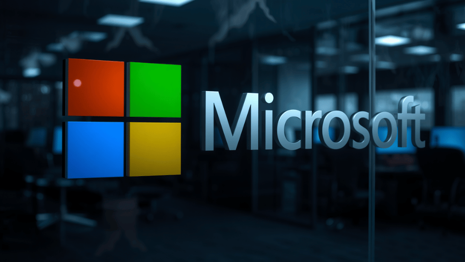A close-up view of a glass office wall featuring the colorful Microsoft corporate logo against a dark background with blurred lights.