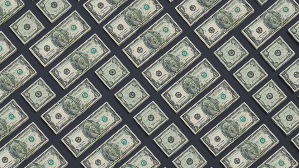 A flat lay photograph showing a neat repeating diagonal pattern of green US dollar bills on a dark background.