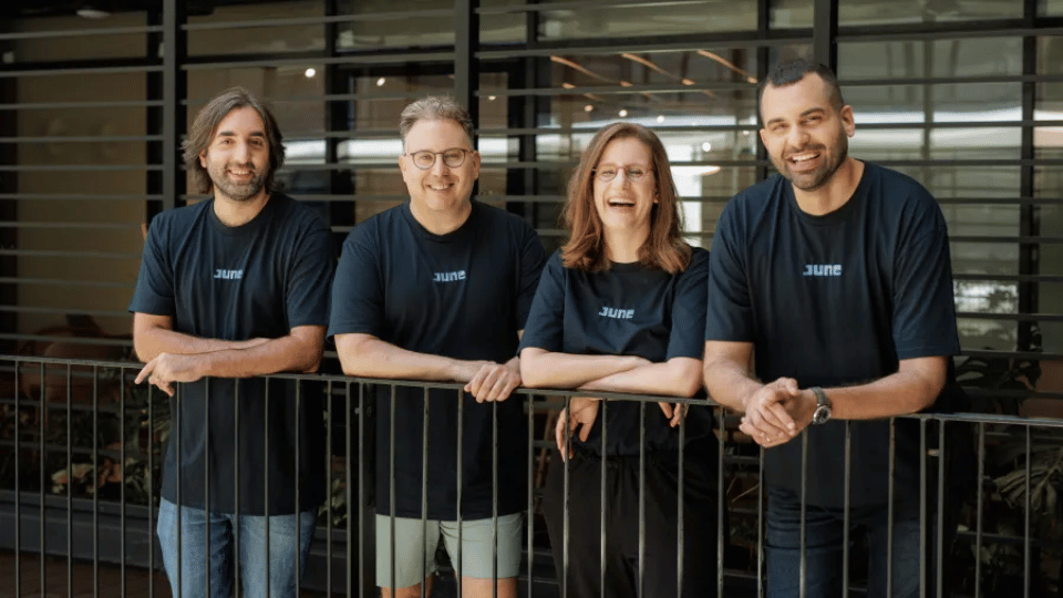 Four startup founders standing together on an outdoor office balcony smiling at the camera.