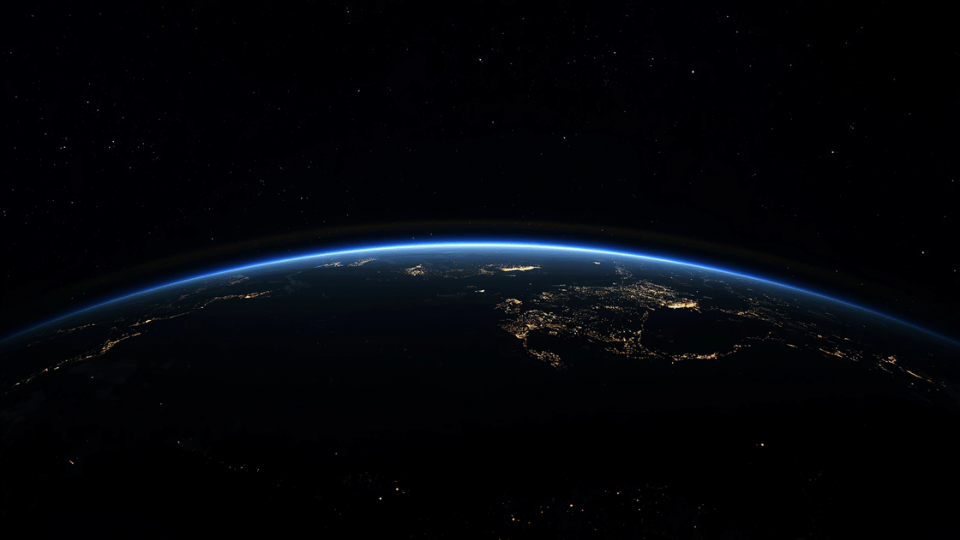 View of Planet Earth from space showing glowing night lights along the curved horizon.