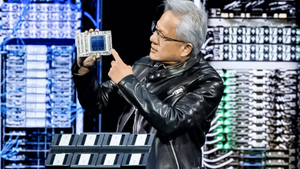 Nvidia CEO Jensen Huang holding up a semiconductor processor chip on stage during a presentation.