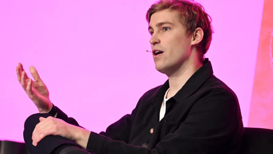 Mati Staniszewski sitting on stage during an executive interview at a technology conference.