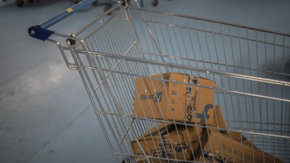 A metal wire shopping cart holding packaged boxes inside a retail store environment.