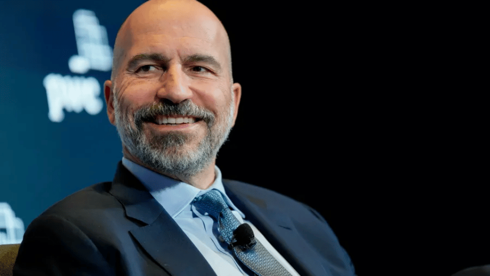 Uber CEO Dara Khosrowshahi wearing a suit and tie speaking at an event.