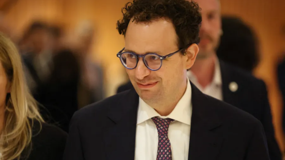 Dario Amodei wearing glasses and a formal suit looking forward.